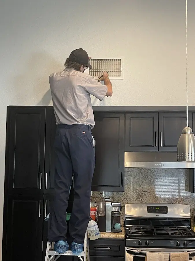 Technician inspecting an air vent during HVAC service in Belle Fourche